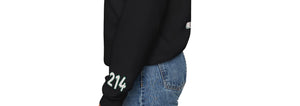 Woman wearing black Dallas hockey sweatshirt showing left sleeve with green “214” graphic and custom sports-inspired patch detailing. Sunday Club fanwear for women.